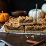 Close-up of Ultimate Fall Apple Crisp Shortbread Bars on a wooden table in a cozy home setting, showcasing their layered apple and shortbread topping, surrounded by autumn decorations for a warm, inviting look.