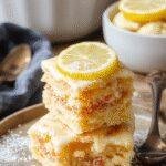 A vibrant assortment of lemon desserts including lemon tarts, lemon bars, and lemon cheesecake garnished with fresh lemon slices and mint leaves.